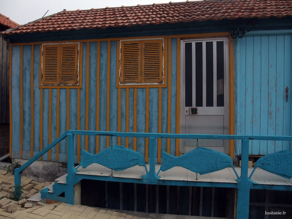 Casa azul, com uma porta de alumínio, e uma porta velha de madeira