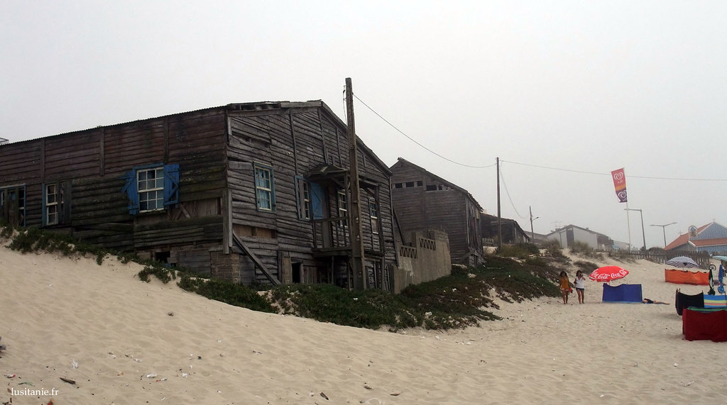 Casas de madeira em ruínas à beira mar, na areia